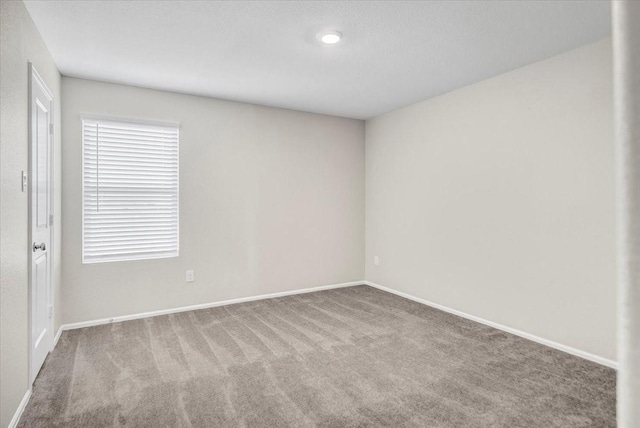 carpeted spare room featuring baseboards