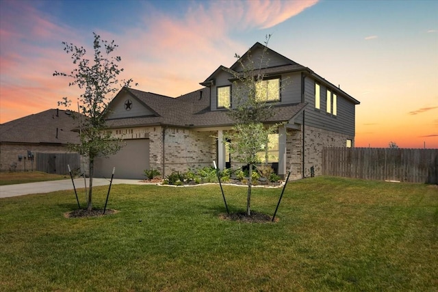 view of front of house featuring a yard, brick siding, driveway, and fence