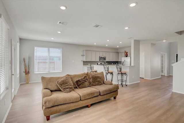 living area with baseboards, light wood finished floors, visible vents, and recessed lighting