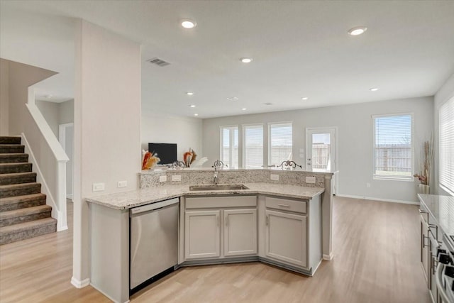 kitchen with visible vents, light wood-style flooring, open floor plan, stainless steel dishwasher, and a sink