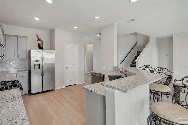 kitchen featuring light stone counters, light wood-style flooring, visible vents, appliances with stainless steel finishes, and gray cabinets