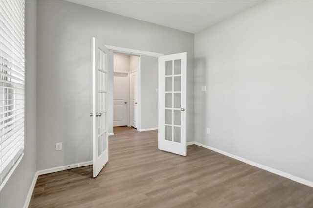 empty room featuring french doors, wood finished floors, and baseboards