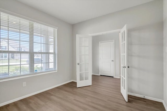 unfurnished bedroom featuring french doors, wood finished floors, and baseboards