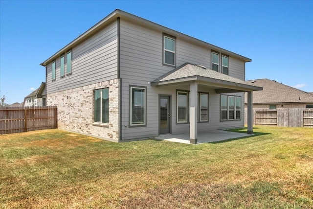 rear view of house featuring a yard, brick siding, a patio area, and a fenced backyard