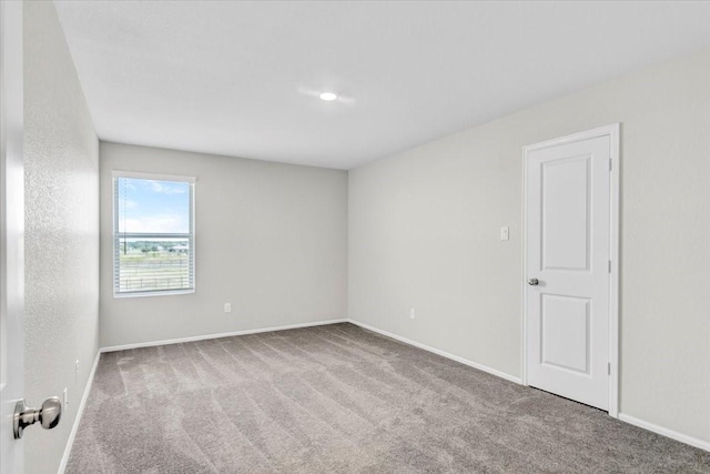 spare room featuring baseboards and light colored carpet