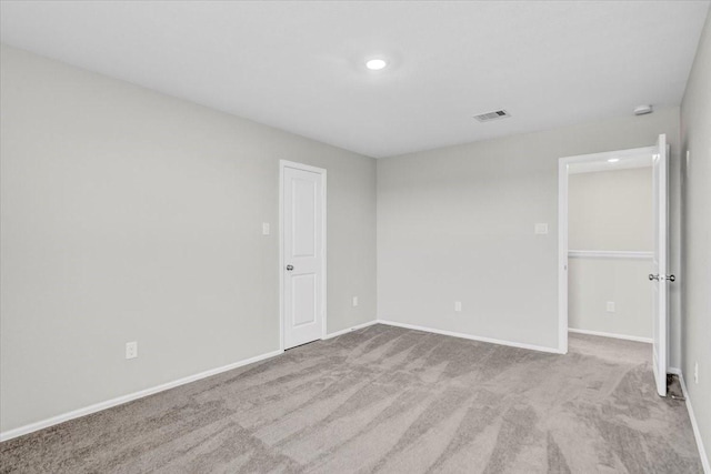 spare room featuring light colored carpet, visible vents, baseboards, and recessed lighting