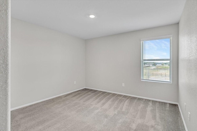 unfurnished room with baseboards and light colored carpet