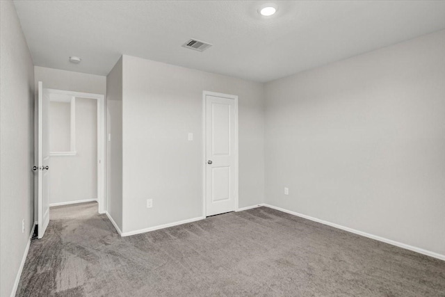 unfurnished bedroom with carpet floors, baseboards, and visible vents