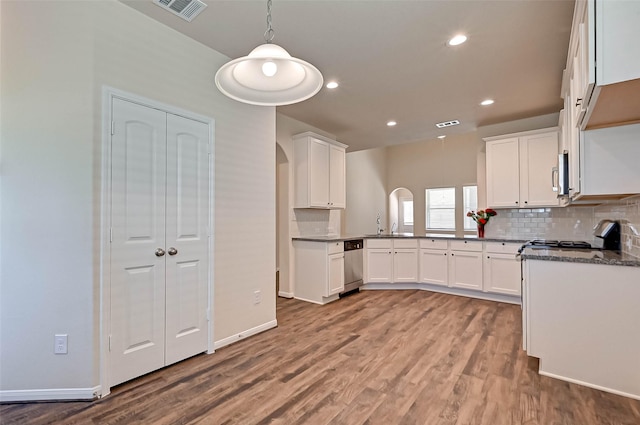 kitchen featuring arched walkways, visible vents, hanging light fixtures, white cabinetry, and wood finished floors