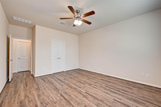 unfurnished bedroom featuring a closet, visible vents, baseboards, and wood finished floors