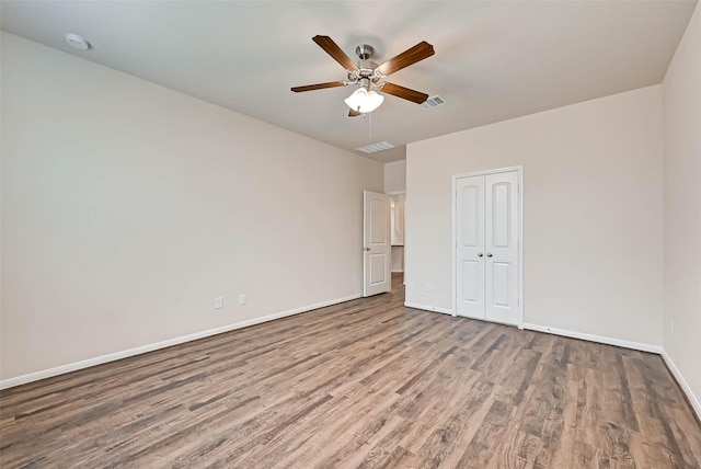 unfurnished bedroom featuring a closet, visible vents, baseboards, and wood finished floors