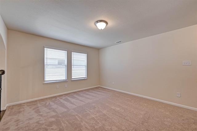 unfurnished room with baseboards, visible vents, and light colored carpet