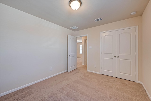 unfurnished bedroom with light carpet, baseboards, visible vents, and a closet