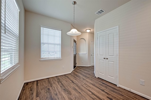 unfurnished dining area with arched walkways, visible vents, dark wood finished floors, and baseboards