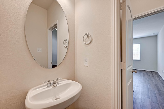 bathroom featuring baseboards, a sink, and wood finished floors