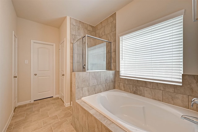 full bath featuring a stall shower, a closet, a bath, and baseboards