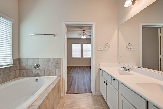 full bathroom featuring double vanity, a ceiling fan, a bath, tile patterned flooring, and a sink