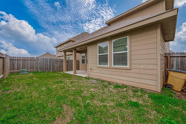 rear view of property featuring a patio area, a yard, and a fenced backyard