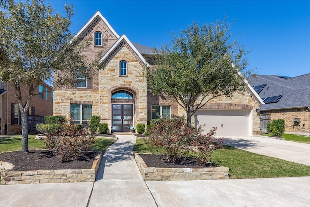 view of front of house featuring concrete driveway, stone siding, an attached garage, french doors, and brick siding