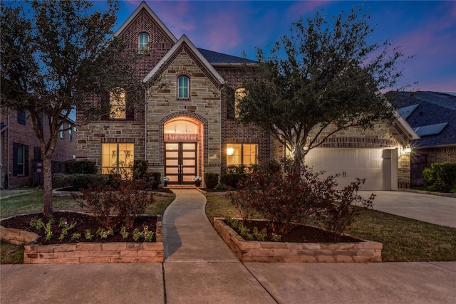 french country style house featuring driveway, french doors, a garage, stone siding, and brick siding