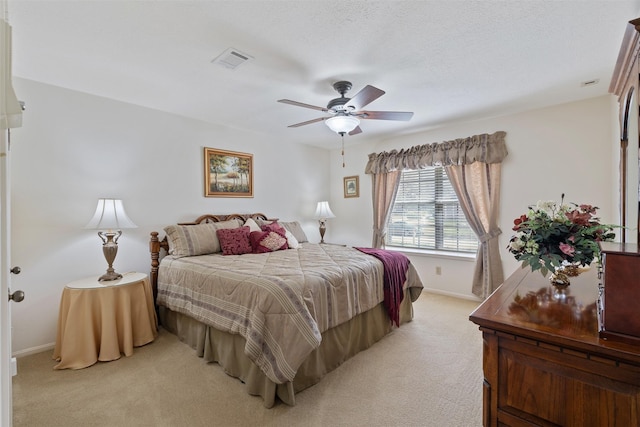 bedroom featuring a textured ceiling, light carpet, visible vents, baseboards, and a ceiling fan