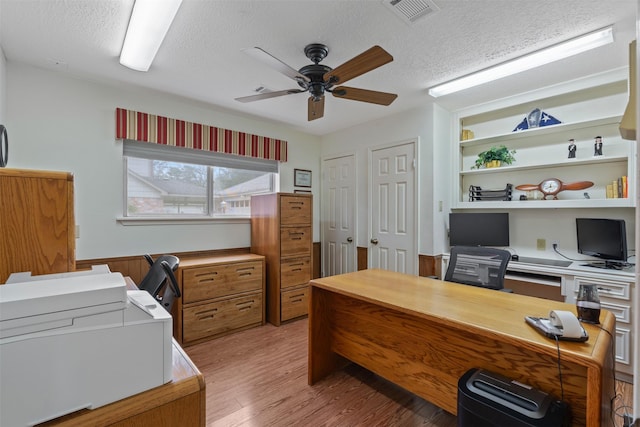 office with visible vents, ceiling fan, light wood-style flooring, and a textured ceiling