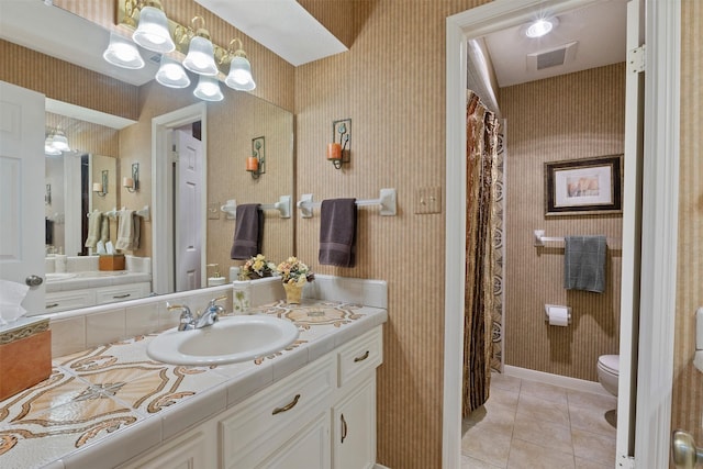 bathroom featuring tile patterned flooring, toilet, vanity, visible vents, and wallpapered walls