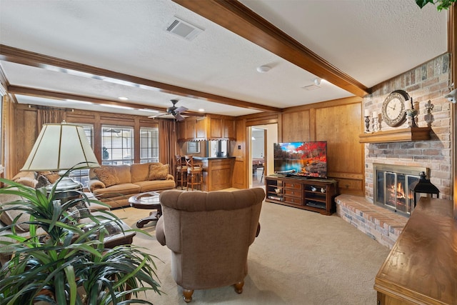 living room featuring a textured ceiling, light colored carpet, visible vents, a brick fireplace, and beam ceiling