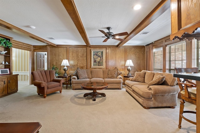 carpeted living area with a textured ceiling, beamed ceiling, and visible vents