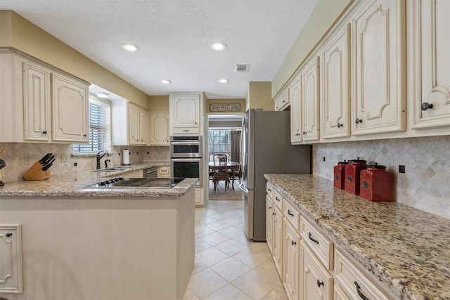 kitchen with light tile patterned floors, visible vents, cream cabinets, stainless steel appliances, and a sink