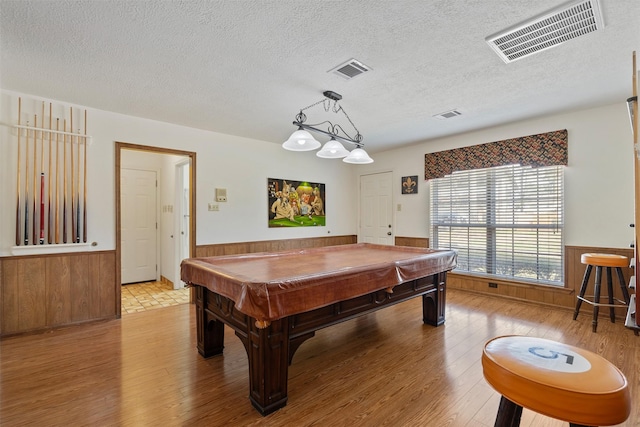 recreation room featuring a wainscoted wall, wooden walls, visible vents, and hardwood / wood-style floors