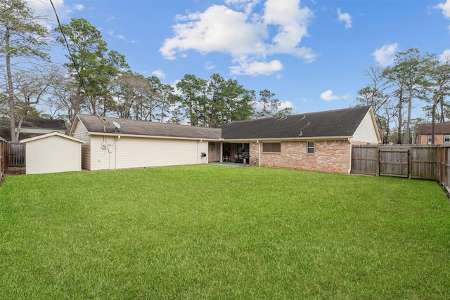 rear view of house with a fenced backyard, a yard, and brick siding