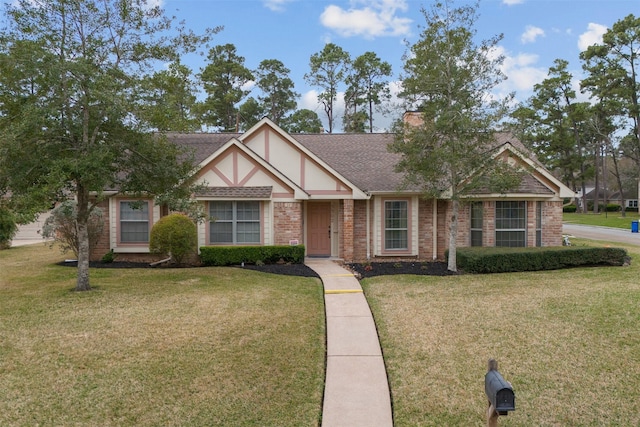 tudor house featuring a shingled roof, brick siding, a chimney, and a front lawn