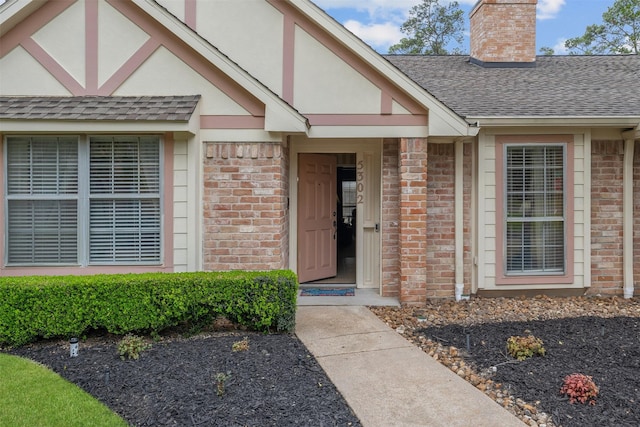 doorway to property with stucco siding, roof with shingles, a chimney, and brick siding