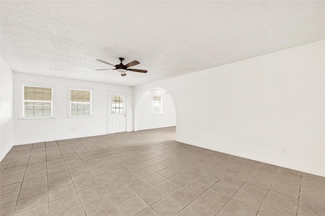 unfurnished living room featuring a textured ceiling, arched walkways, and a ceiling fan