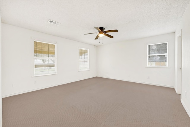 carpeted spare room featuring a textured ceiling, ceiling fan, visible vents, and baseboards