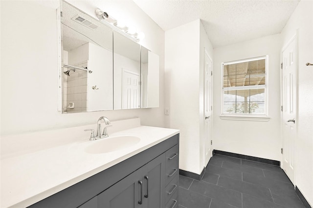 full bath with visible vents, a textured ceiling, vanity, baseboards, and tile patterned floors