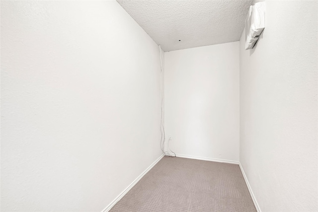 empty room featuring carpet flooring, a textured ceiling, and baseboards