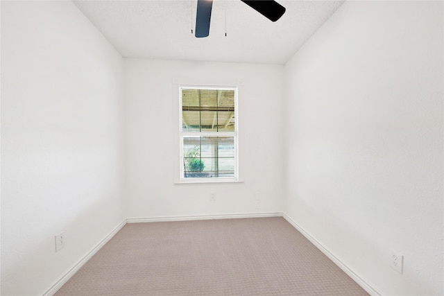 unfurnished room featuring a ceiling fan, light colored carpet, and baseboards