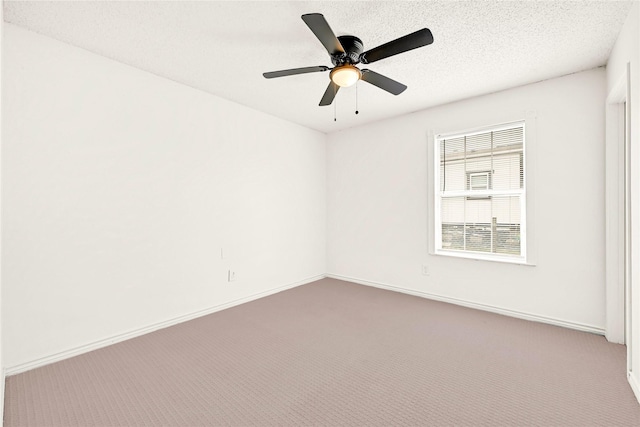 spare room with a textured ceiling, carpet flooring, and baseboards