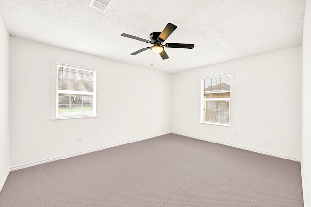 spare room featuring plenty of natural light, a textured ceiling, carpet, and visible vents