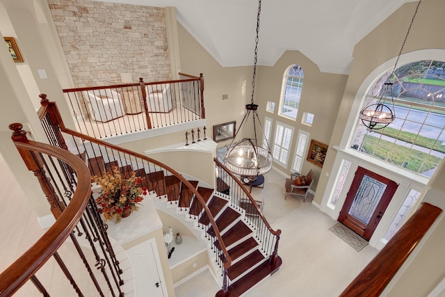 entrance foyer with an inviting chandelier, stairs, and high vaulted ceiling