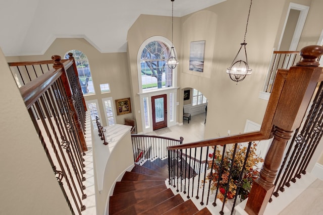 entryway featuring a chandelier, high vaulted ceiling, plenty of natural light, and crown molding