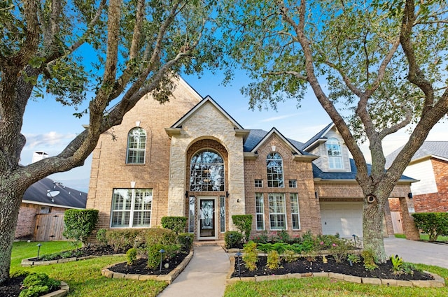 traditional home featuring driveway, a front yard, fence, and brick siding