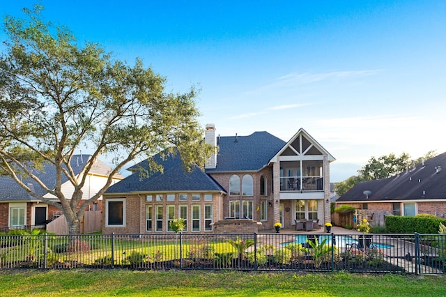 rear view of house featuring a fenced in pool, a patio, a chimney, a sunroom, and fence private yard