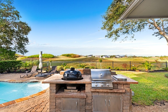 view of patio featuring a fenced backyard, a fenced in pool, exterior kitchen, and area for grilling