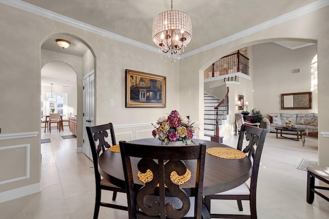 dining space featuring a chandelier, a decorative wall, arched walkways, and crown molding