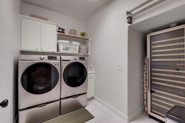 laundry room featuring beverage cooler, washing machine and clothes dryer, cabinet space, and baseboards