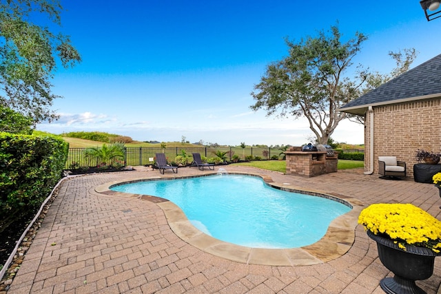 view of swimming pool with a patio, an outdoor kitchen, a fenced backyard, and a fenced in pool