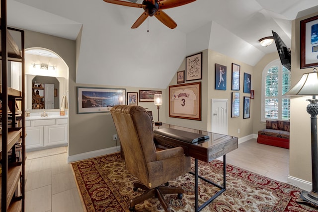 home office featuring baseboards, arched walkways, a ceiling fan, lofted ceiling, and a sink